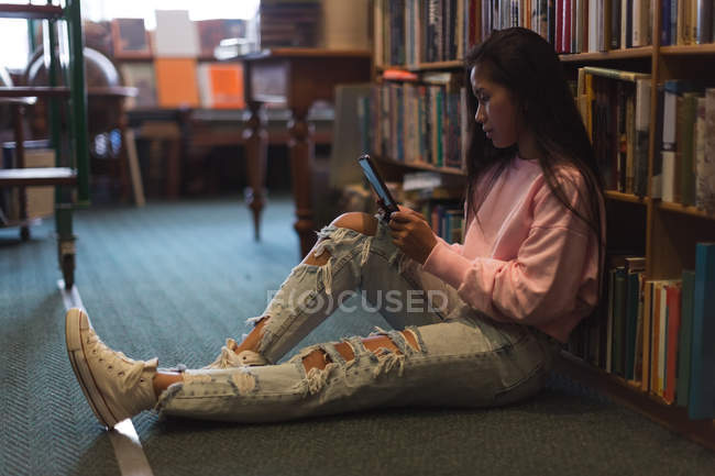 Adolescente usando tablet digital na biblioteca — Fotografia de Stock