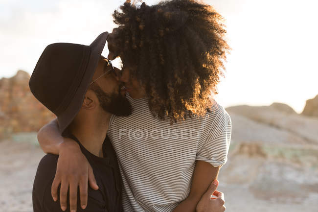 Casal romântico beijando uns aos outros na praia durante o pôr do sol — Fotografia de Stock
