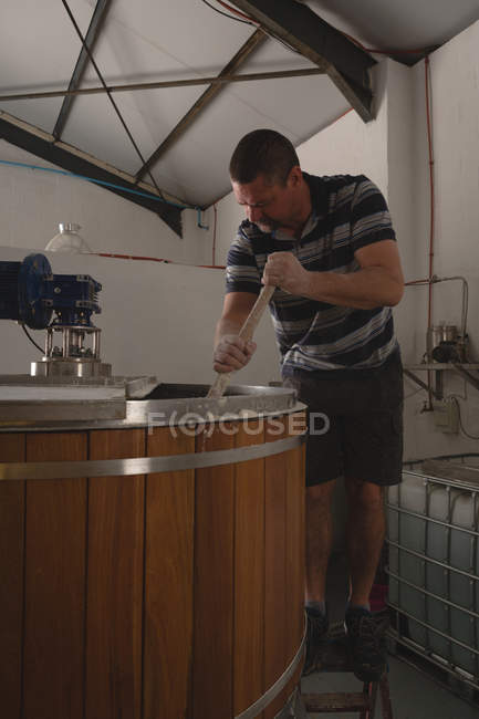 Работник мужского пола, перемешивающий джин на заводе — стоковое фото