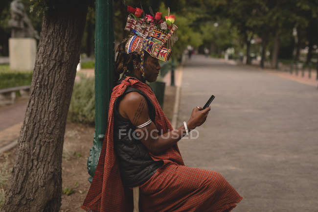 Uomo Maasai in abbigliamento tradizionale utilizzando il telefono cellulare su strada — Foto stock