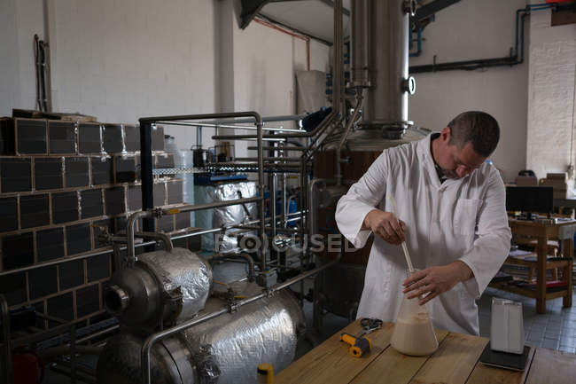 Trabalhador verificando a qualidade do gin na fábrica — Fotografia de Stock