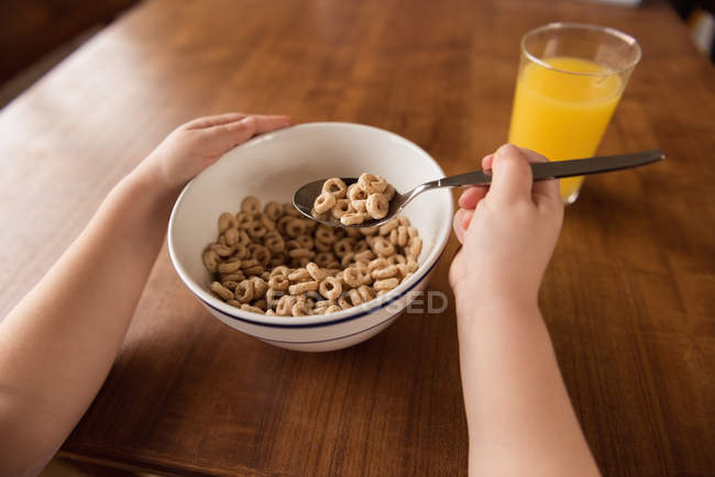 Ragazza che fa colazione cereali e succo di frutta sul tavolo a casa — Foto stock