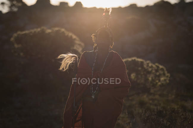 Uomo Maasai in abiti tradizionali in piedi con bastone in campagna — Foto stock