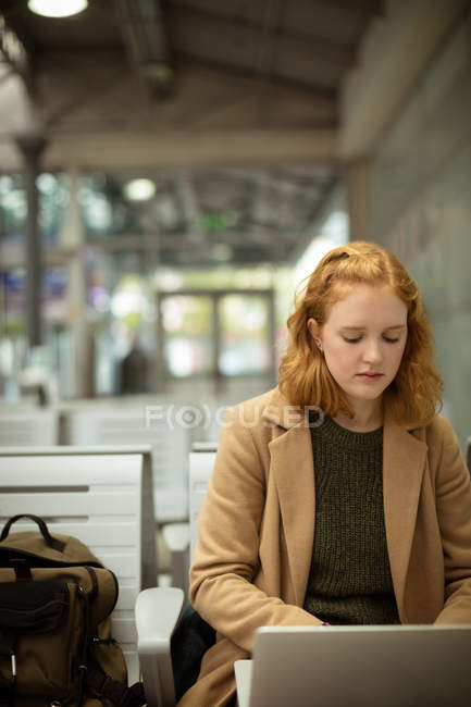 Молода жінка використовує свій ноутбук на автобусній зупинці — стокове фото