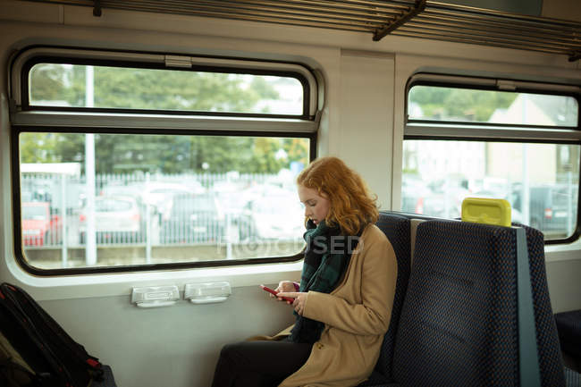 Cabelo vermelho jovem mulher usando seu celular no trem — Fotografia de Stock
