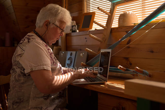 Seniorin benutzt Laptop am Schreibtisch in Fabrik — Stockfoto
