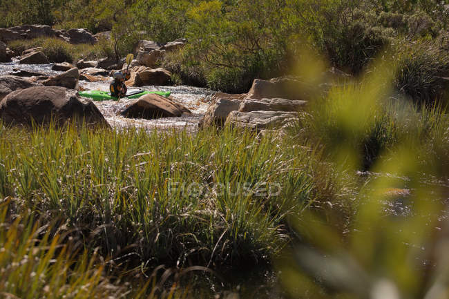 Жінка катається на байдарках в скелястій річці на сонячному світлі . — стокове фото