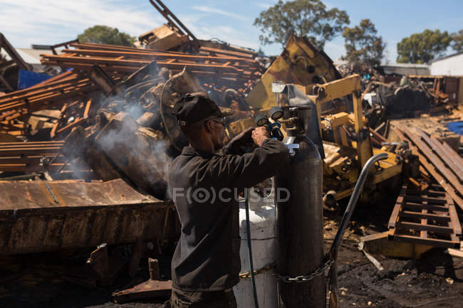 Trabajador cerrando el grifo del cilindro en el desguace - foto de stock