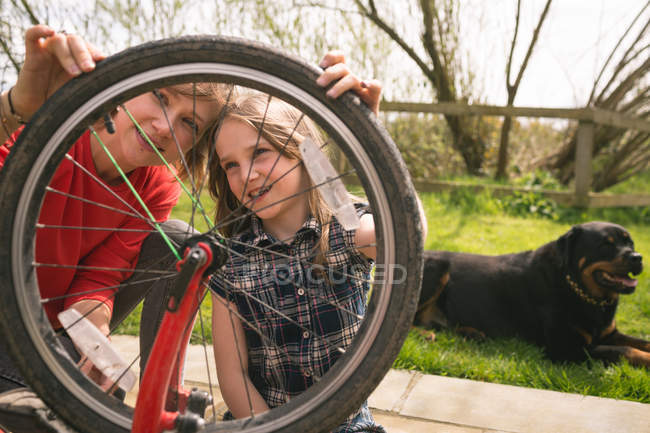 Madre e hija reparando la bicicleta juntas en el patio trasero - foto de stock