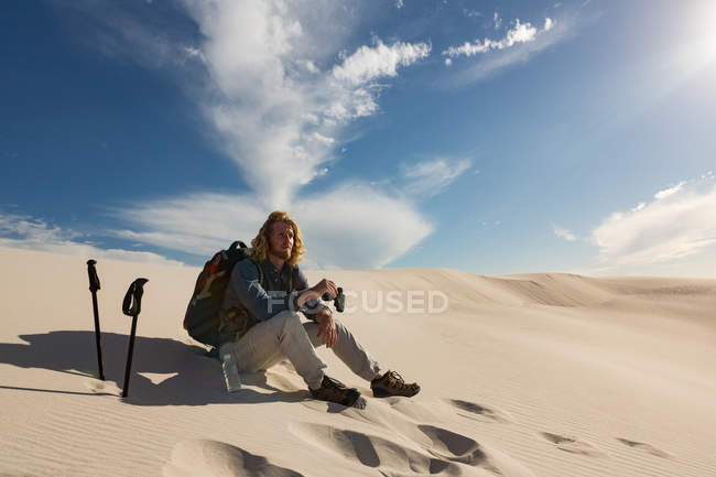 Male hiker relaxing on sand in the desert — Stock Photo