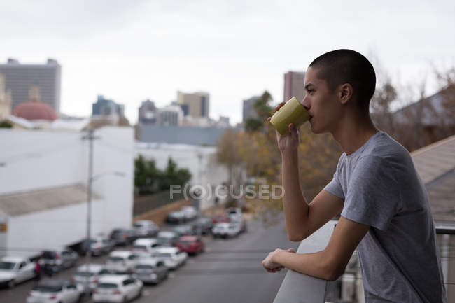 Jovem tomando café na varanda em casa — Fotografia de Stock