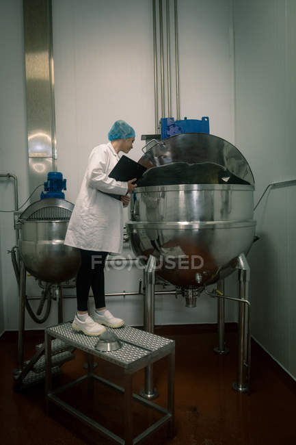 Female worker inspecting the food production line in food factory — Stock Photo