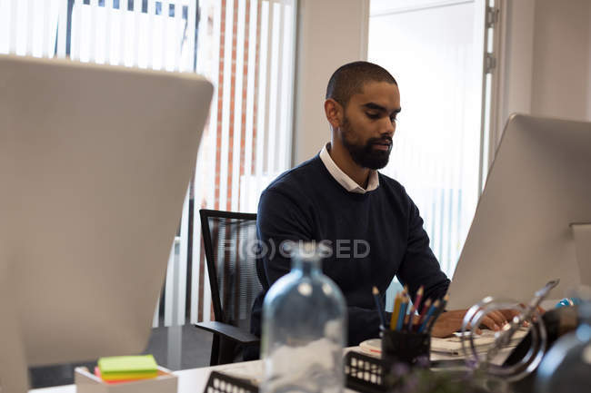 Чоловік, який працює на комп'ютері в офісі — стокове фото