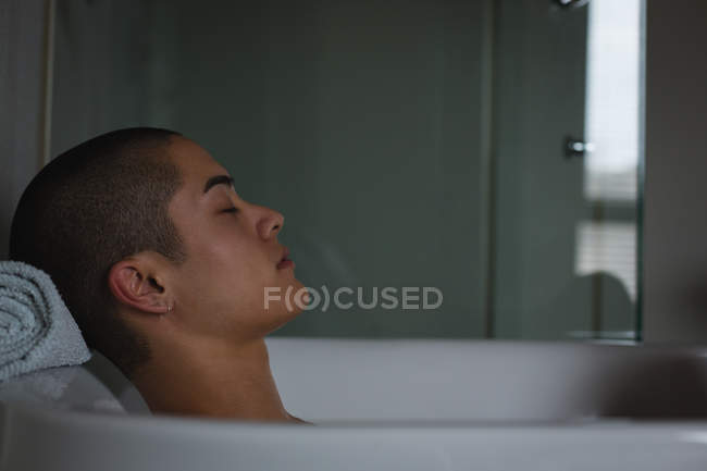Jeune homme relaxant dans la baignoire à la salle de bain — Photo de stock