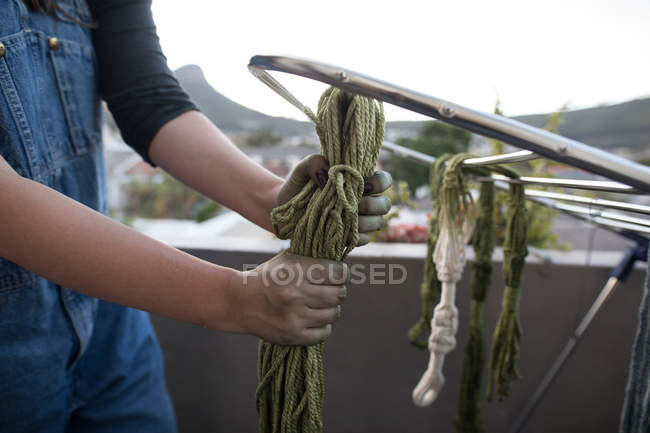 Mid section of woman drying dyed thread on rack in balcony — Stock Photo