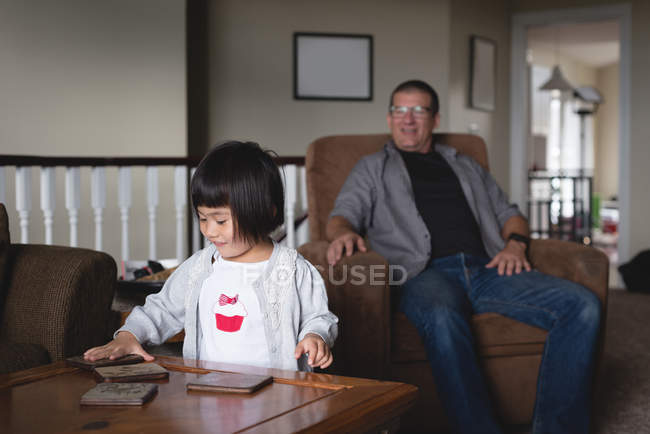 Fille debout près de la table tandis que père la regardant à la maison — Photo de stock