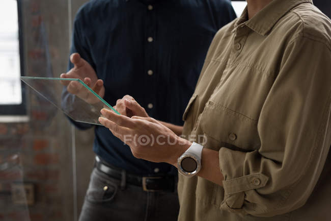 Business colleagues discussing over glass digital tablet. — Stock Photo