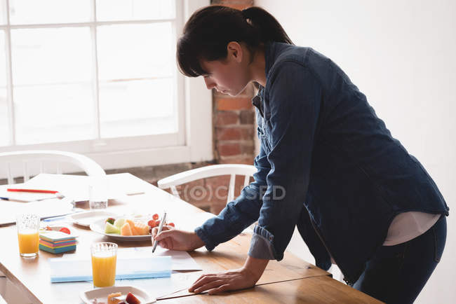 Exécutif féminin vérifiant un document dans le bureau de création — Photo de stock