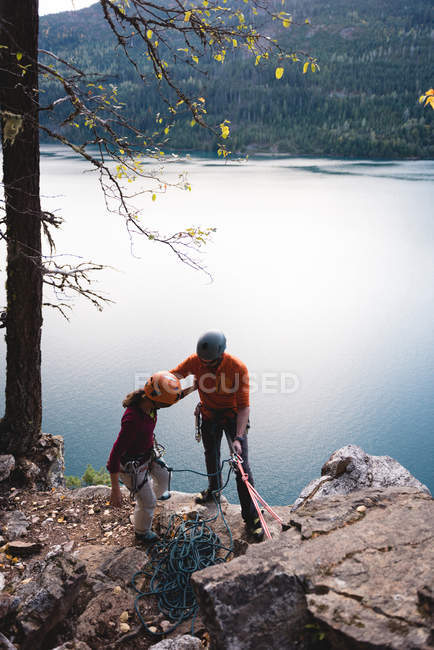 Casal preparando-se para subir a montanha rochosa perto do lago — Fotografia de Stock