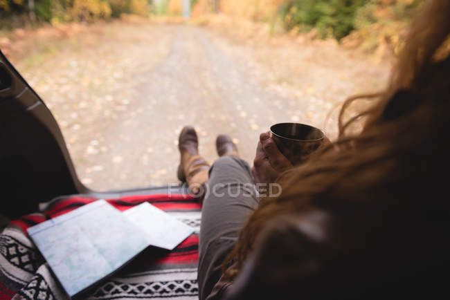 Visão traseira da mulher com xícara de café sentado no parque de outono — Fotografia de Stock
