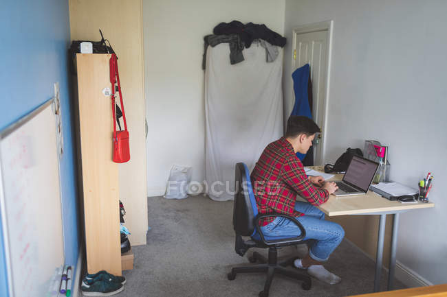 Jovem trabalhando com laptop na mesa em casa interior . — Fotografia de Stock