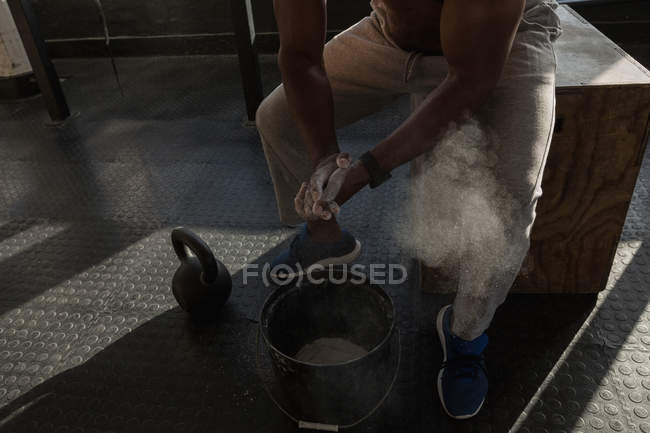 Cropped view of mature man rubbing white powder on hands before workout. — Stock Photo