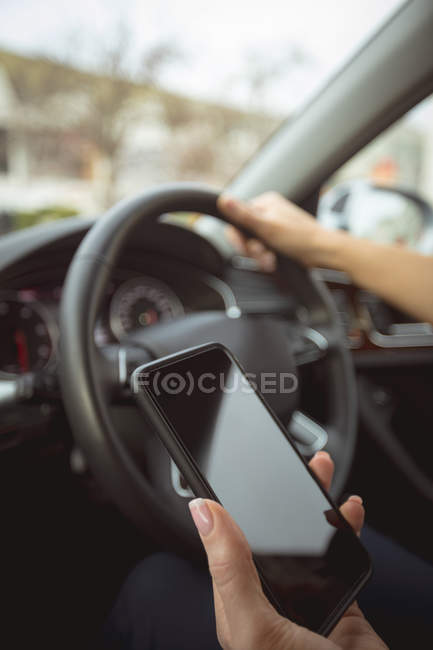 Крупный план женщины-руководителя с помощью мобильного телефона во время вождения автомобиля — стоковое фото