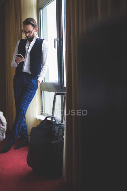 Empresário usando telefone celular no quarto de hotel — Fotografia de Stock