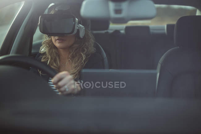 Bella dirigente femminile utilizzando cuffie realtà virtuale durante la guida di una macchina — Foto stock