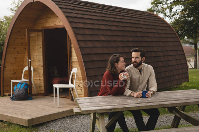 Happy couple having coffee outside the log cabin — Stock Photo