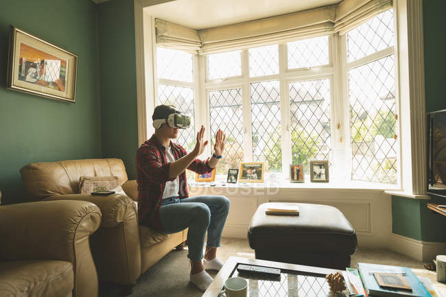 Человек, использующий гарнитуру виртуальной реальности в гостиной дома . — стоковое фото