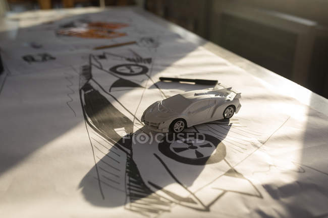 Автомобільна модель на графіку та ескізи на столі в офісі . — стокове фото