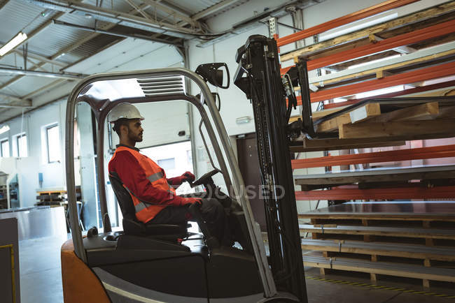 Travailleur masculin conduisant un chariot élévateur dans l'entrepôt — Photo de stock