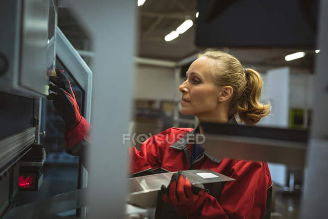 Женщина-работница проверяет машину на заводе — стоковое фото