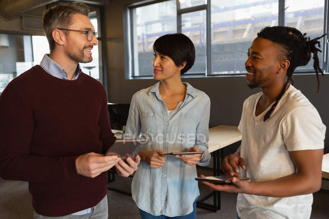 Executives talking and using tablet computers in office. — Stock Photo