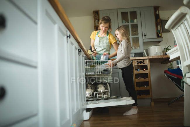 Mutter und Tochter ordnen zu Hause Utensilien in Küchenschränken — Stockfoto