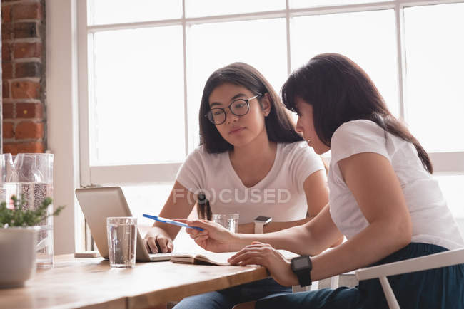 Женщины-руководители обсуждают за ноутбуком в креативном офисе — стоковое фото