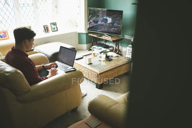 Man using laptop in armchair in living room at home. — Stock Photo