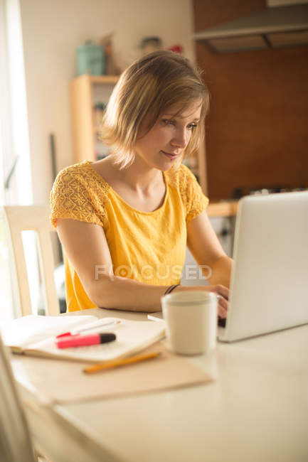 Woman using laptop in kitchen at home — Stock Photo