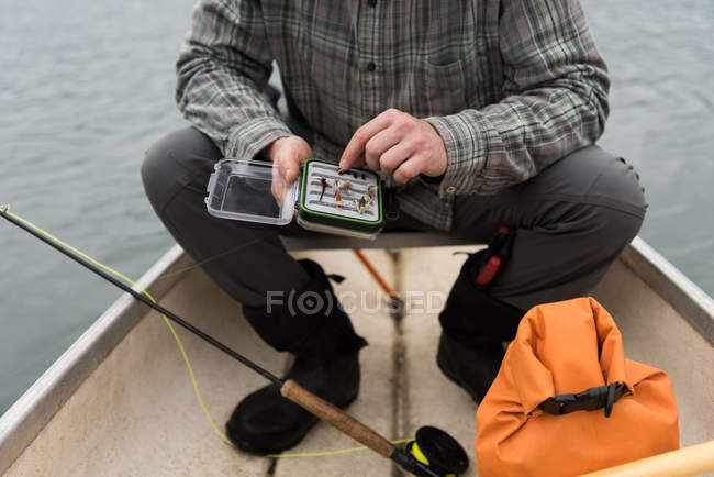 Человек в лодке с коробкой приманки в руках — стоковое фото