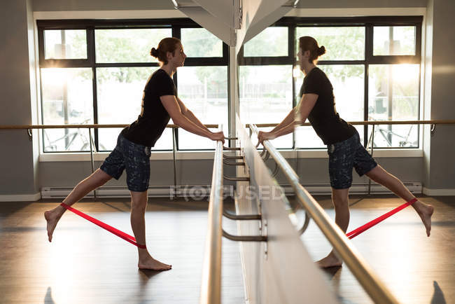Man exercising with resistance band in fitness studio. — Stock Photo