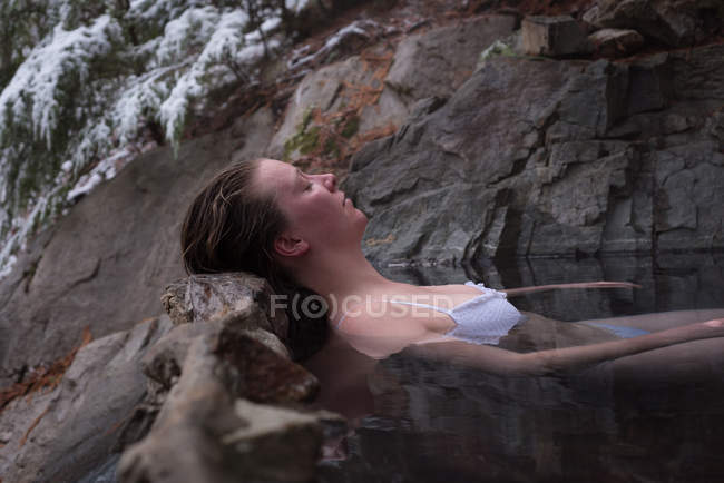 Attractive woman relaxing in hot spring during winter — Stock Photo