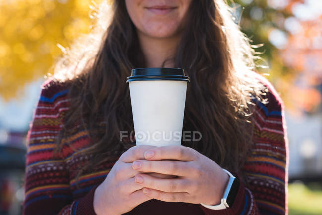 Mid section of woman holding coffee in disposable glass on a sunny day — Stock Photo