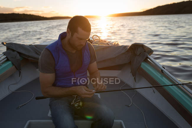 Attentive man tying fishing rod in motorboat. — Stock Photo