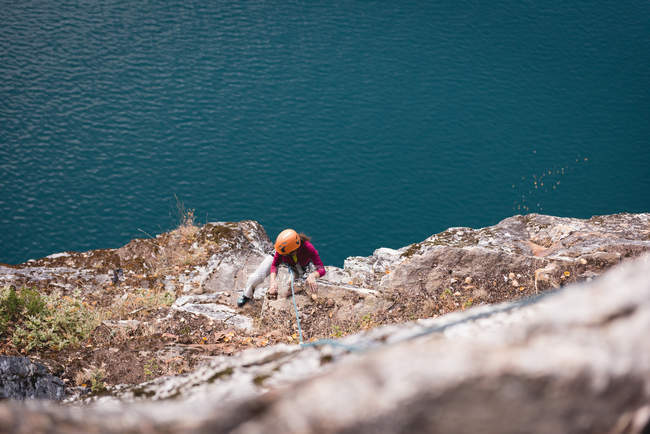 Sobre la cabeza de la escaladora escalando la montaña rocosa - foto de stock