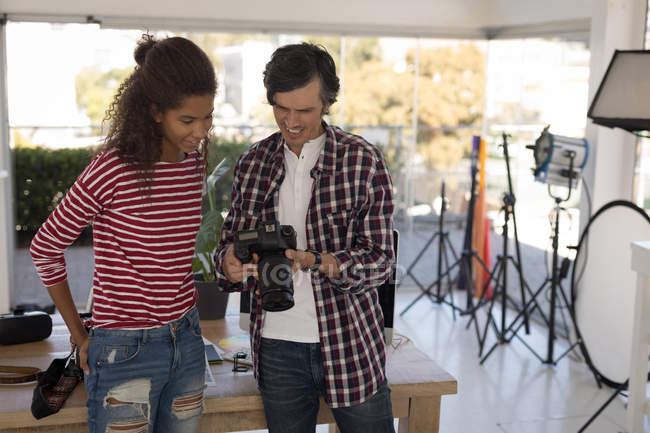 Photographe montrant des photos au mannequin de mode sur appareil photo numérique en studio — Photo de stock