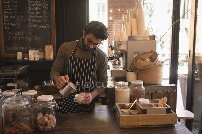 Barista gießt Milch in eine Tasse an der Theke im Café — Stockfoto