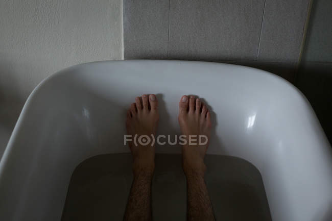 Низкая часть человека, отдыхающего в ванне в ванной комнате — стоковое фото