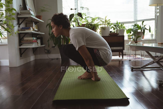 Молодая женщина, занимающаяся йогой на коврике для йоги дома — стоковое фото