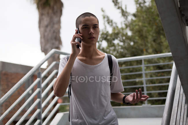 Молодой человек разговаривает по мобильному телефону на лестнице — стоковое фото